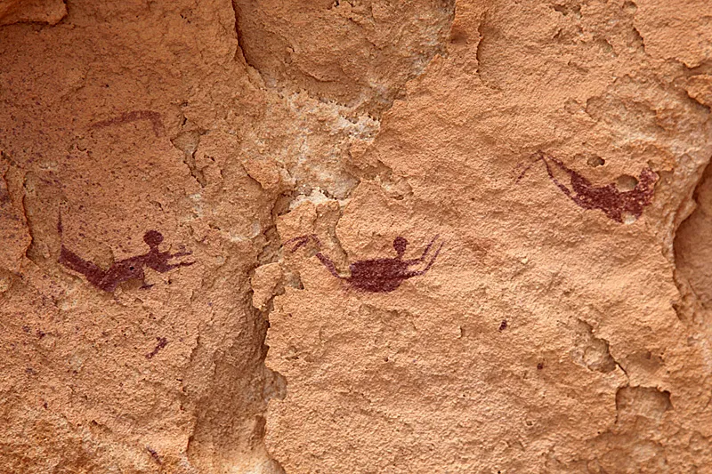 Painted human figures in a rock shelter, seen from the side in postures that look like swimming.