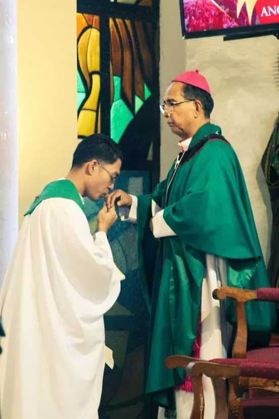 An altar server kisses the bishop’s hand, in a church of today.