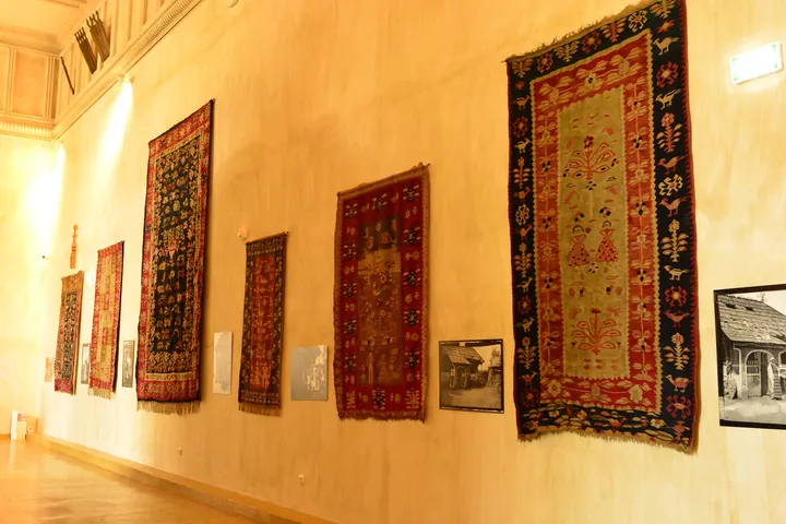 Five traditional carpets displayed on a museum wall.
