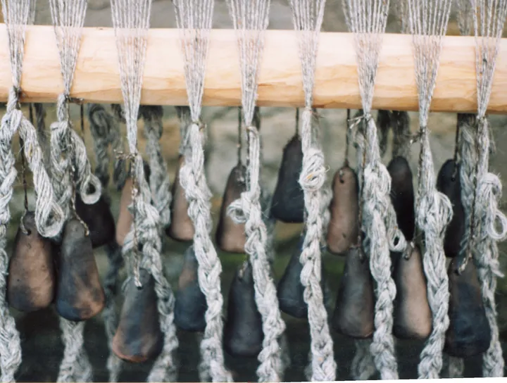 Pyramidal clay weights hanging from warp threads.