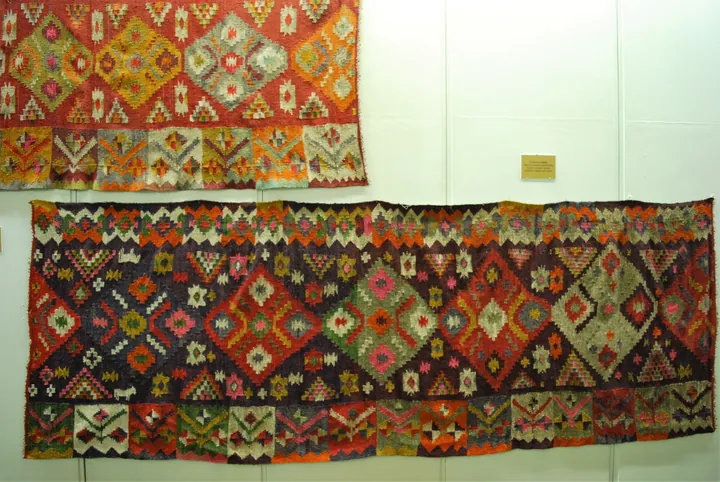 Maramureș carpets with colourful rhombi in a museum.
