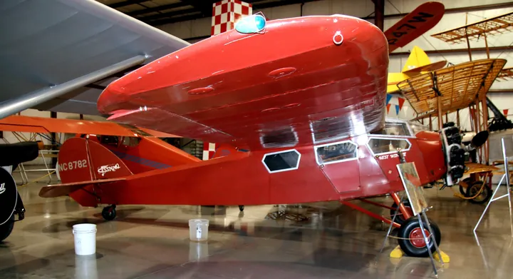 Red 1929 high-wing Cessna monoplane on display in a museum hangar.