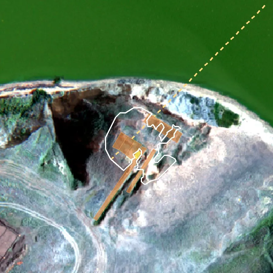 Drone photograph seen from above, north up: the green lake at the top, the cliff, and on the terrace the mound outlined in white; the excavation trenches are coloured ochre; the dashed 130-metre line runs out over the cliff and the water.