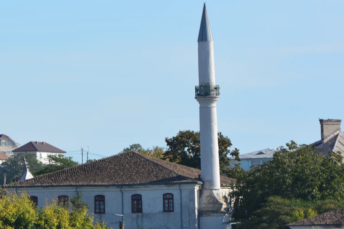 Minaretul și acoperișul geamiei Azizyie între casele Tulcei, văzute dinspre Dunăre