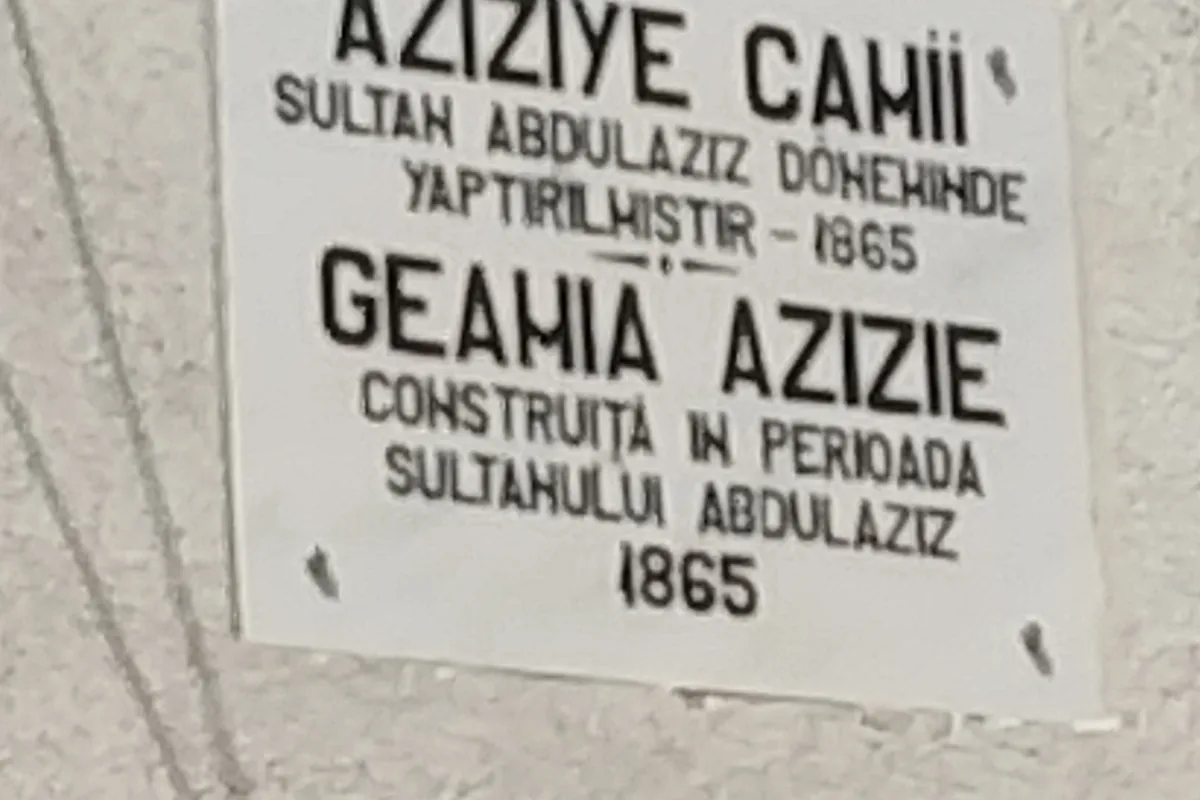 Placa albă de pe zidul geamiei, cu text în turcă și română și anul 1865