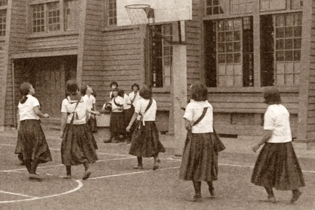 Eleve japoneze în bluze albe și fuste plisate închise, jucându-se în curtea unei școli din Tokio, 1936.