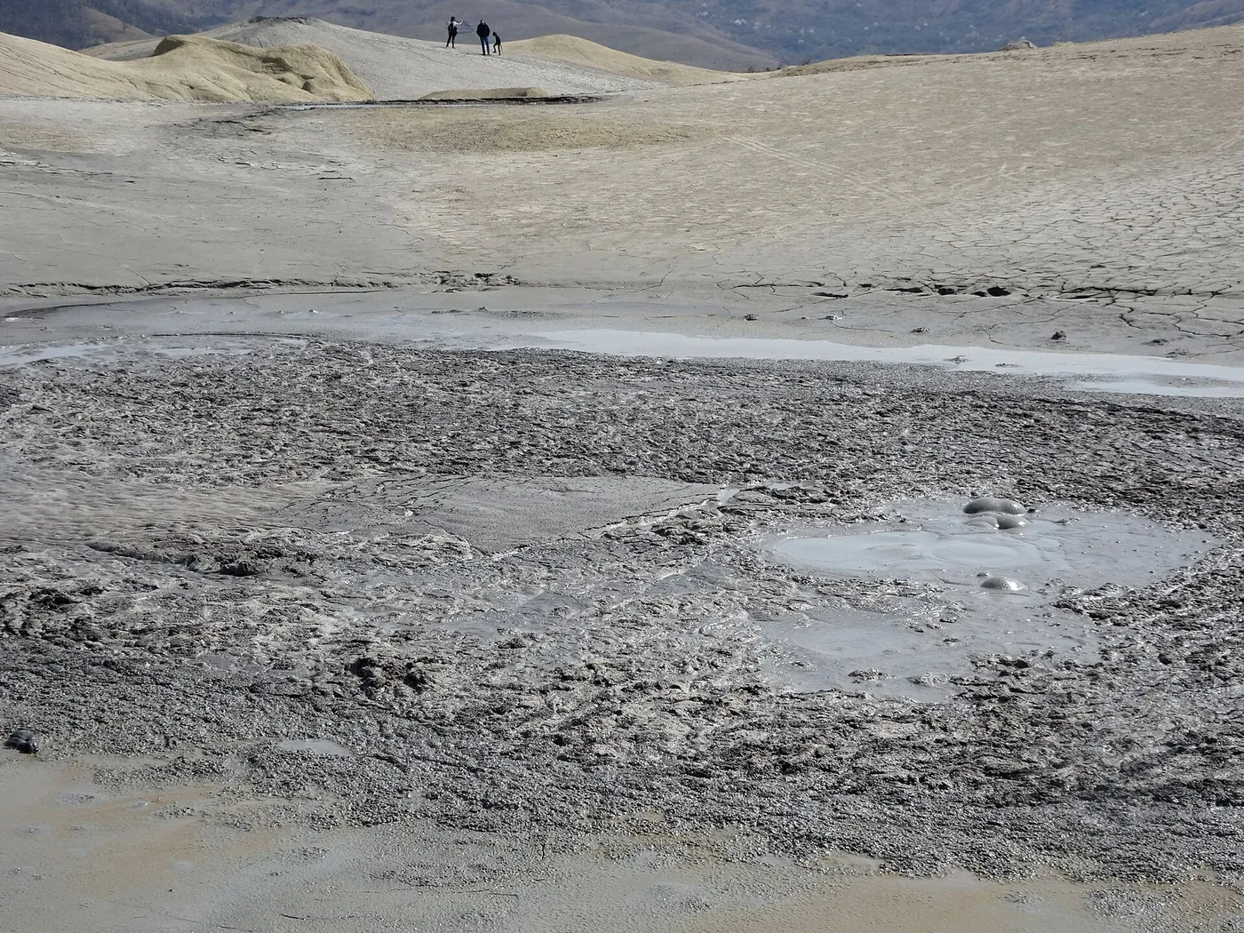 Pools of liquid mud with gas bubbles swelling in them.